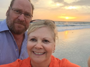 Couple smiling at the camera with a view of sunset behind  